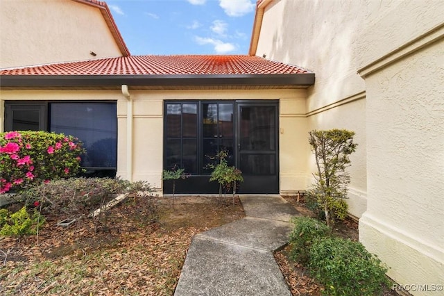 doorway to property featuring a tile roof and stucco siding