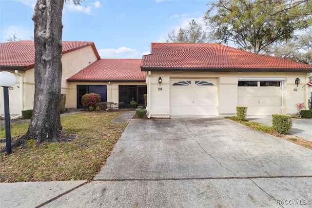 mediterranean / spanish-style house with driveway, stucco siding, and a tiled roof