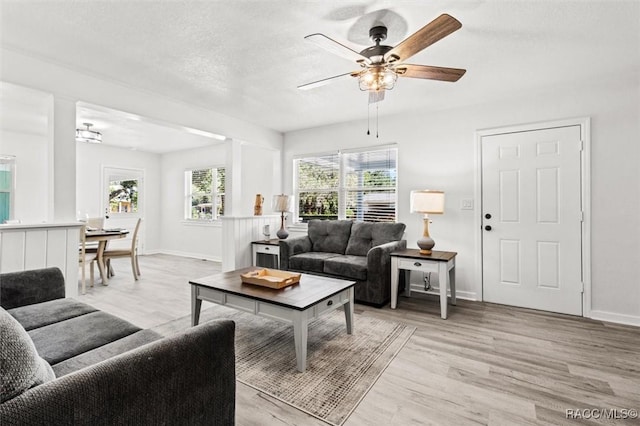 living room featuring ceiling fan, a textured ceiling, and light hardwood / wood-style floors