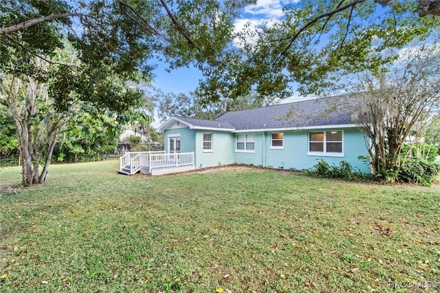 rear view of property featuring a deck and a lawn