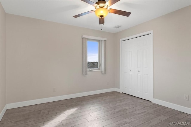 unfurnished bedroom featuring ceiling fan, light hardwood / wood-style floors, and a closet