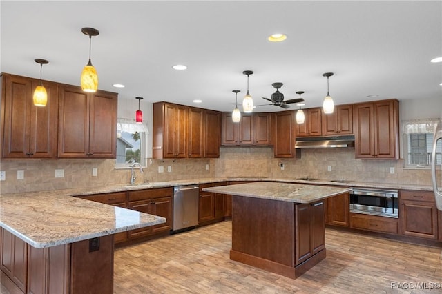 kitchen featuring pendant lighting, sink, appliances with stainless steel finishes, a center island, and light hardwood / wood-style floors