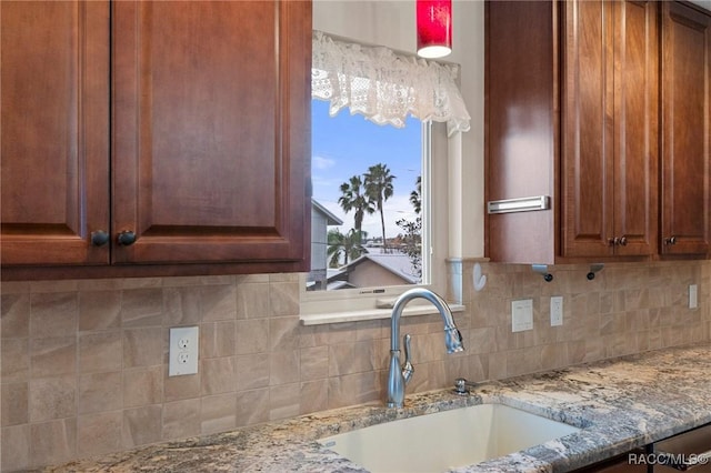 kitchen featuring sink, light stone counters, and decorative backsplash