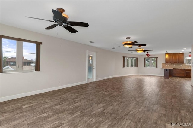 unfurnished living room featuring dark wood-type flooring and ceiling fan