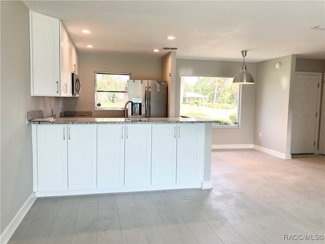 kitchen featuring light hardwood / wood-style floors, white cabinetry, hanging light fixtures, and appliances with stainless steel finishes