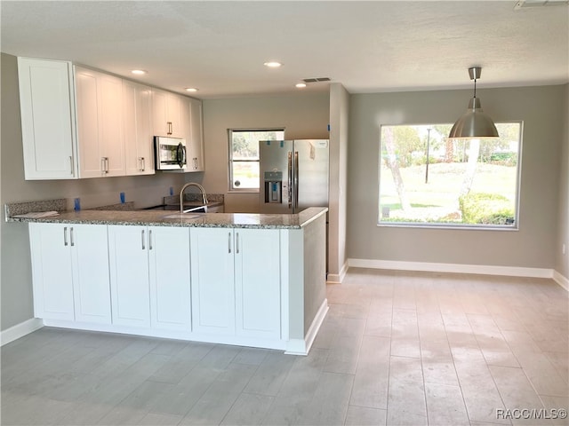 kitchen featuring kitchen peninsula, stainless steel appliances, white cabinets, and dark stone countertops