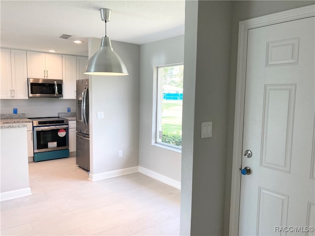 kitchen featuring white cabinetry, hanging light fixtures, light wood-type flooring, and appliances with stainless steel finishes