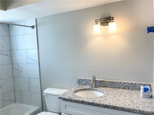 full bathroom featuring tiled shower / bath, vanity, and toilet