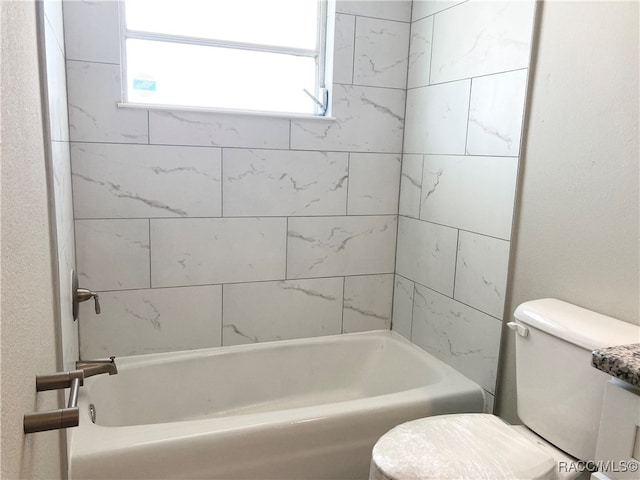 bathroom featuring tiled shower / bath combo and toilet