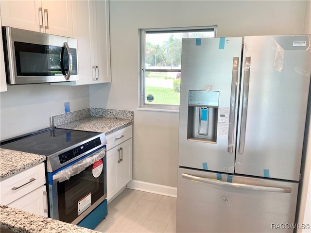 kitchen with light stone countertops, white cabinets, and appliances with stainless steel finishes