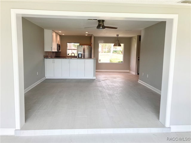 unfurnished living room with light hardwood / wood-style flooring, ceiling fan, and sink