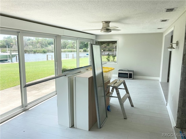 sunroom / solarium featuring heating unit, ceiling fan, and a water view