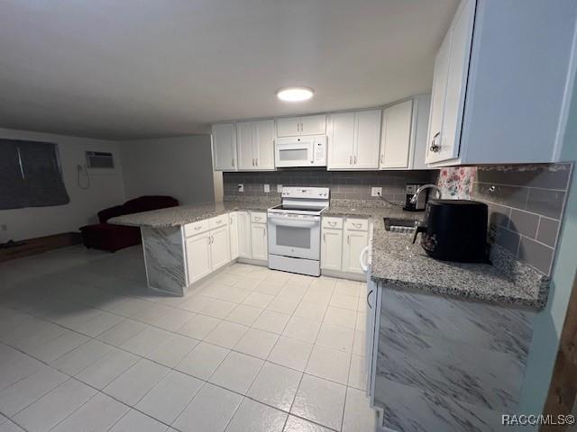 kitchen with light stone countertops, backsplash, white appliances, sink, and white cabinets