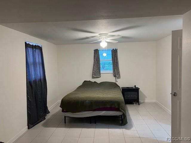 tiled bedroom featuring ceiling fan