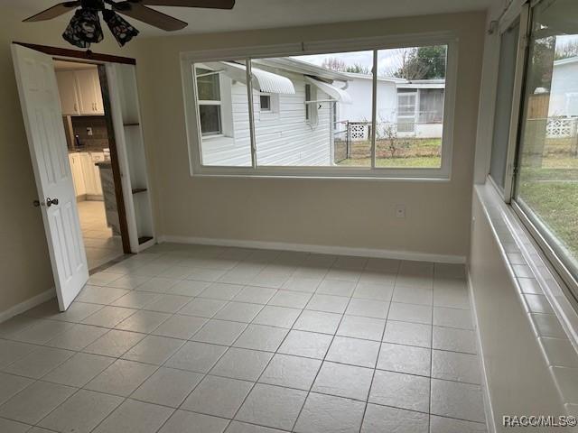 tiled spare room featuring ceiling fan