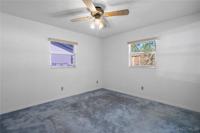 spare room with ceiling fan, dark colored carpet, and a textured ceiling