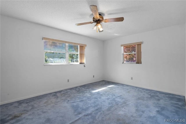 unfurnished room with dark carpet, ceiling fan, and a textured ceiling