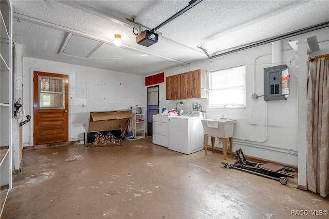 garage featuring washing machine and dryer, electric panel, a garage door opener, and sink