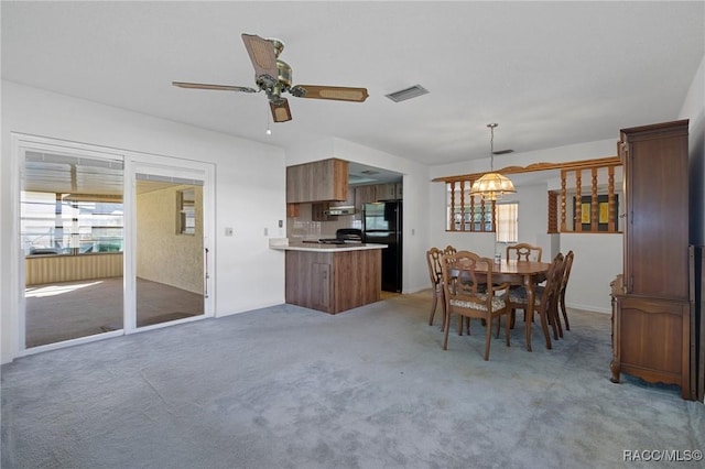 carpeted dining area with ceiling fan with notable chandelier