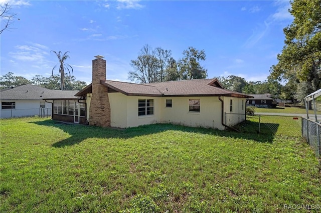 rear view of house with a sunroom and a lawn