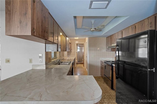 kitchen with sink, a tray ceiling, ceiling fan, black appliances, and kitchen peninsula