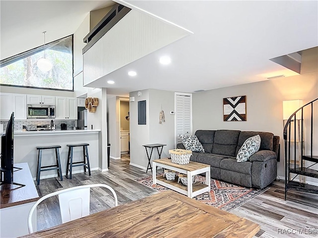 living area with recessed lighting, baseboards, light wood-style flooring, and stairway