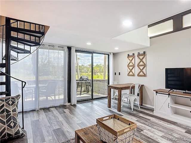 living room featuring floor to ceiling windows, wood finished floors, stairway, baseboards, and recessed lighting