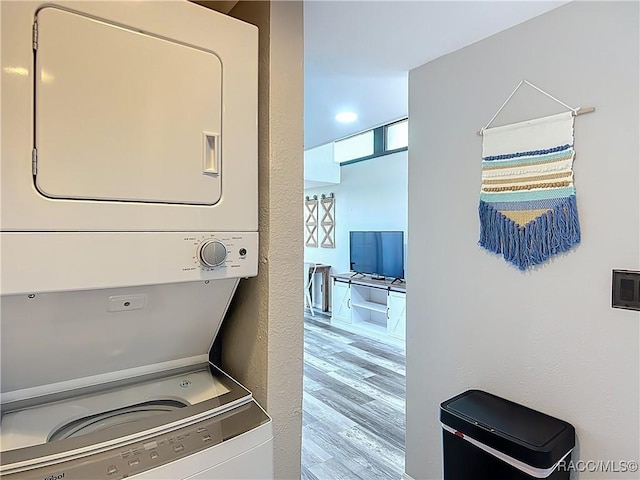 laundry room featuring laundry area, stacked washer / drying machine, and wood finished floors