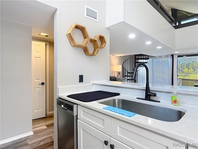 kitchen featuring visible vents, wood finished floors, dishwasher, a sink, and white cabinets