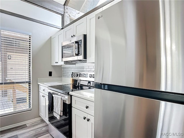 kitchen featuring white cabinets, light wood-style floors, light countertops, stainless steel appliances, and tasteful backsplash