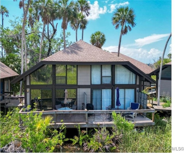 back of house featuring a shingled roof and a wooden deck