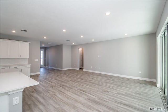 unfurnished living room featuring light wood-type flooring, baseboards, visible vents, and recessed lighting