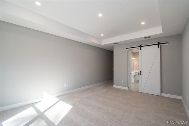 unfurnished bedroom with recessed lighting, a raised ceiling, visible vents, a barn door, and baseboards