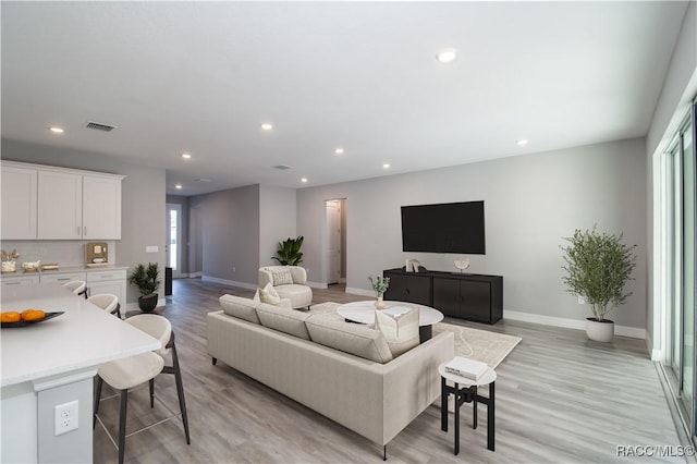 living area with baseboards, light wood-type flooring, visible vents, and recessed lighting