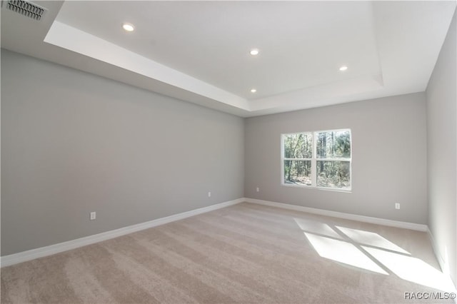 spare room with a tray ceiling, visible vents, baseboards, and recessed lighting