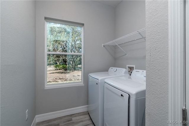 clothes washing area with a healthy amount of sunlight, laundry area, baseboards, and washer and clothes dryer