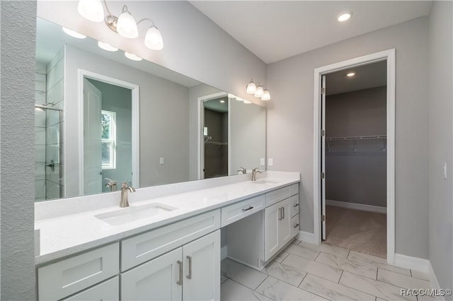 full bath featuring marble finish floor, double vanity, a sink, and a tile shower