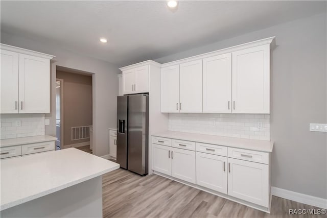 kitchen featuring white cabinetry, backsplash, light hardwood / wood-style floors, and stainless steel fridge with ice dispenser