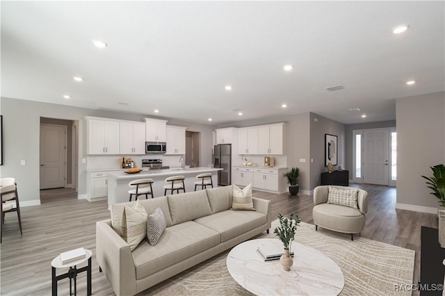 living room with recessed lighting, visible vents, and baseboards