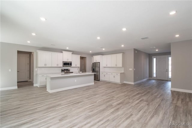 kitchen with a kitchen island with sink, recessed lighting, stainless steel appliances, visible vents, and open floor plan