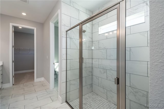 bathroom featuring a stall shower, marble finish floor, baseboards, and toilet