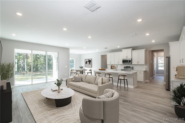 living area with a wealth of natural light, recessed lighting, visible vents, and light wood finished floors