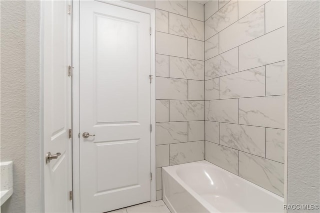 full bathroom featuring a textured wall and shower / tub combination