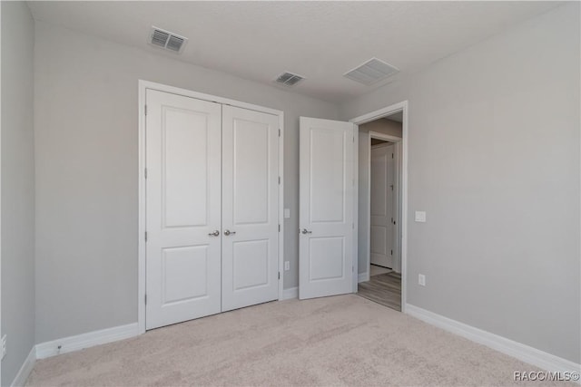 unfurnished bedroom featuring a closet, light carpet, visible vents, and baseboards