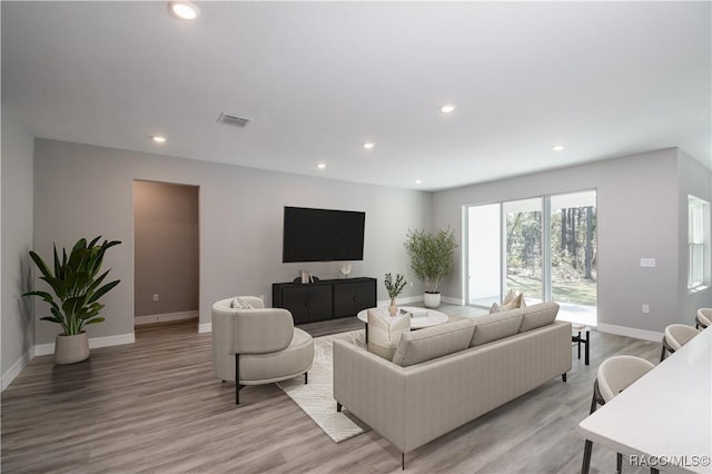 living room with light wood finished floors, visible vents, and recessed lighting