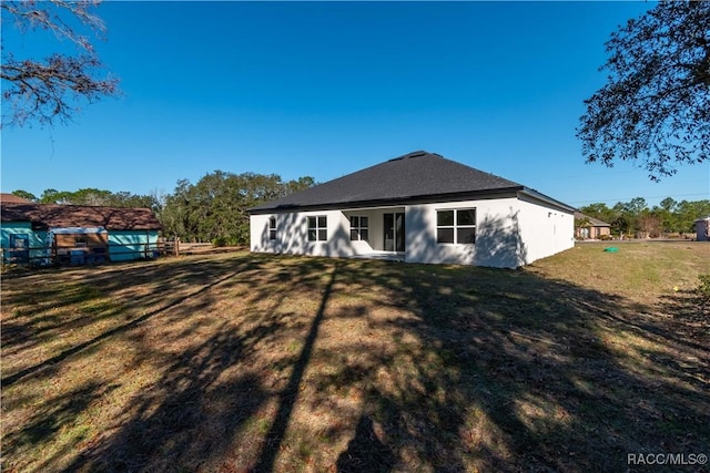 back of house with a yard and stucco siding