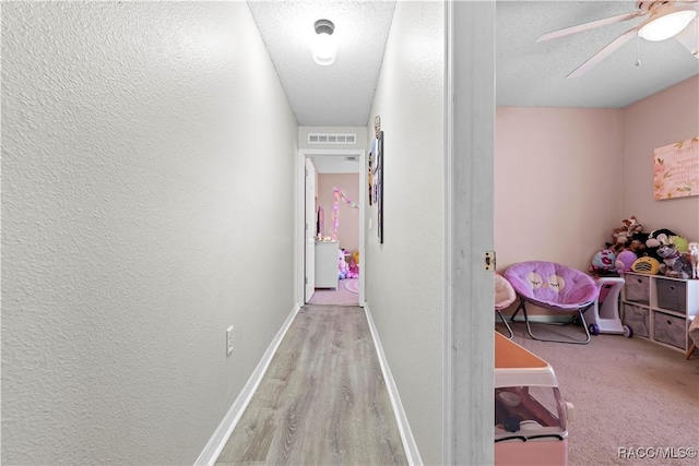 hallway featuring light hardwood / wood-style flooring and a textured ceiling