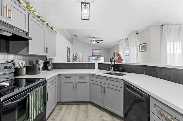 kitchen featuring black appliances, gray cabinetry, lofted ceiling, and sink