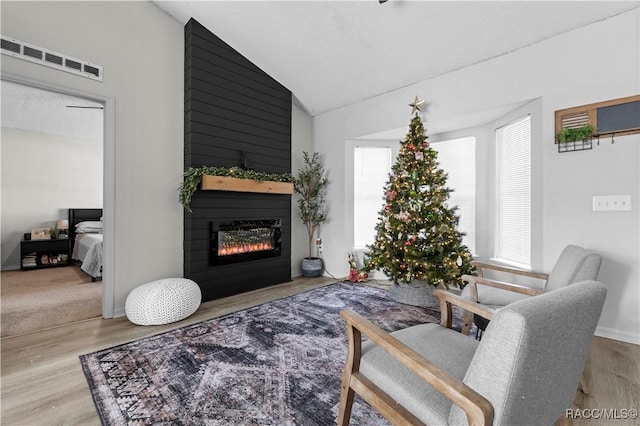 living room featuring a textured ceiling, a fireplace, vaulted ceiling, and light wood-type flooring