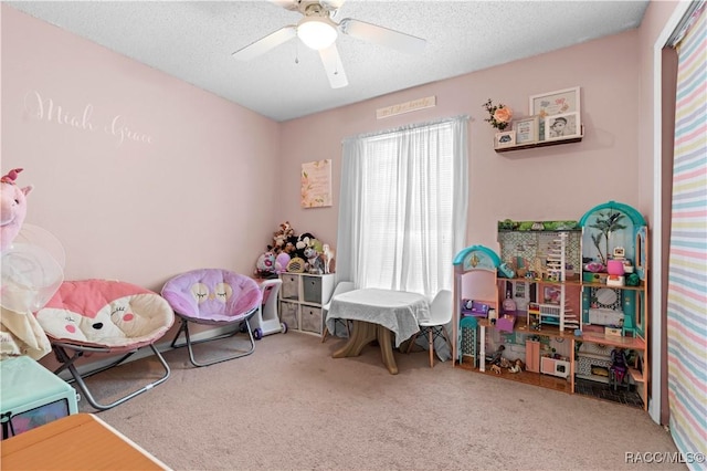 playroom featuring carpet, ceiling fan, and a textured ceiling